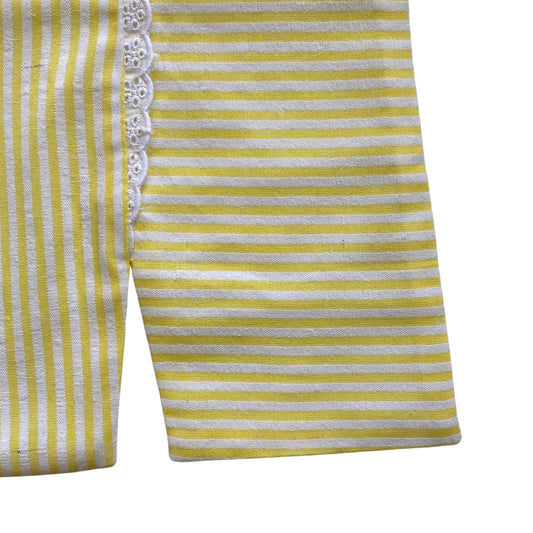 Yellow and white striped garment with lace trim on a white background. Split hem top