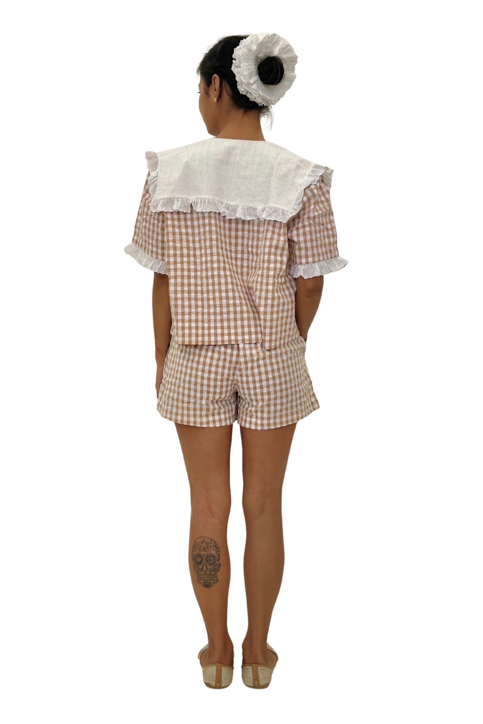 Person wearing a checkered outfit with lace details on a white background. Gingham set. Cute short set.