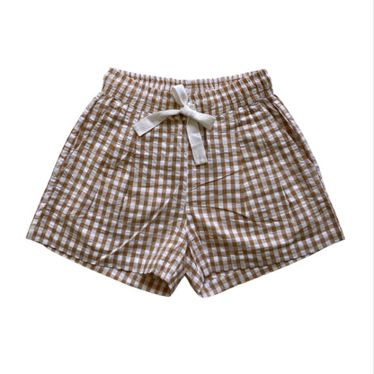 Brown and white checkered shorts with a bow on a white background. Seersucker gingham elasticated shorts with twill tie. Organic Cotton Fabric.