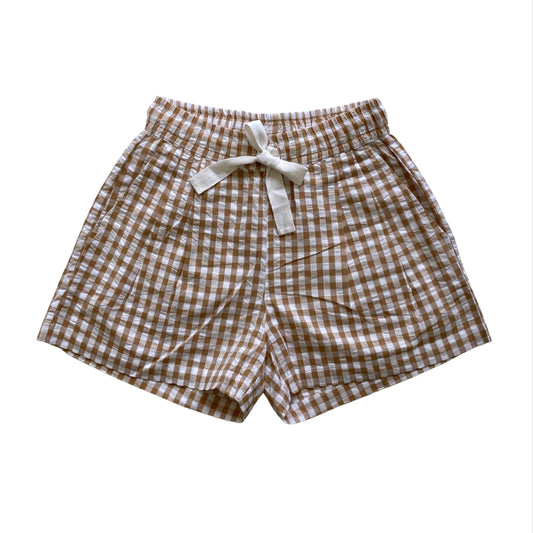 Brown and white checkered shorts with a bow on a white background. Seersucker gingham elasticated shorts with twill tie. Organic Cotton Fabric.