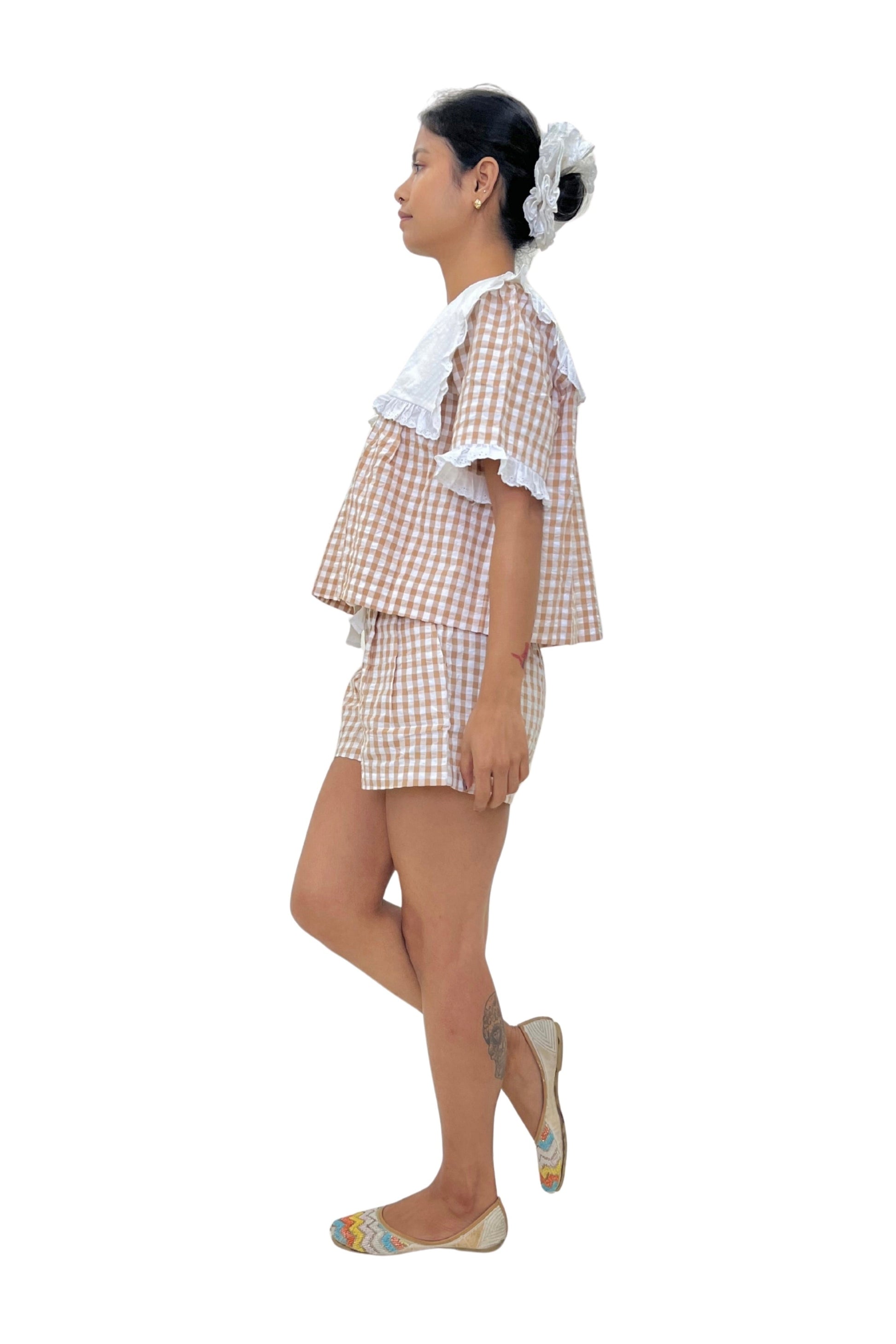 Woman wearing a checkered outfit on a white background. Brown Gingham Set. Organic Cotton Set.