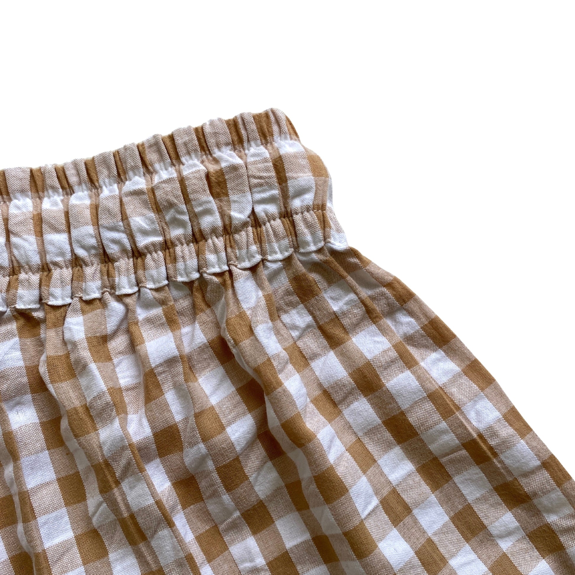 Brown and white checkered shorts on a white background. Elasticated waist. Waistband.