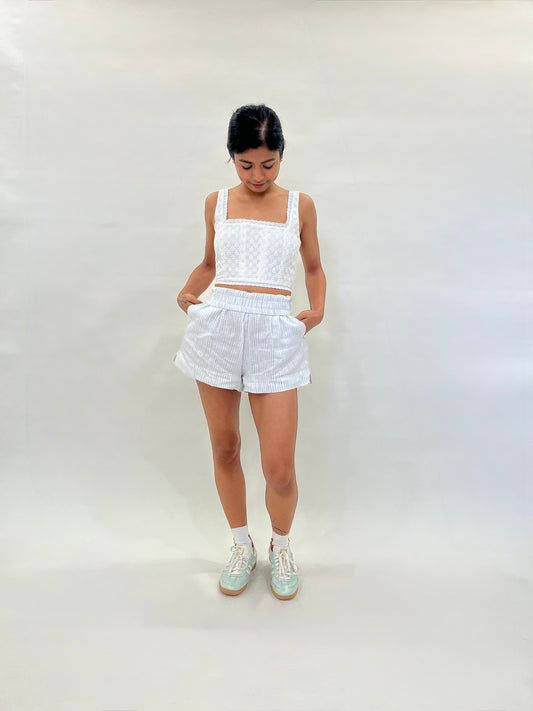 Model wearing a white corset with striped linen elasticated shorts  on a plain background