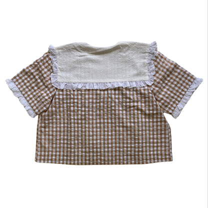 Checkered shirt with white collar and lace ruffles on a white background. Seersucker organic cotton top.