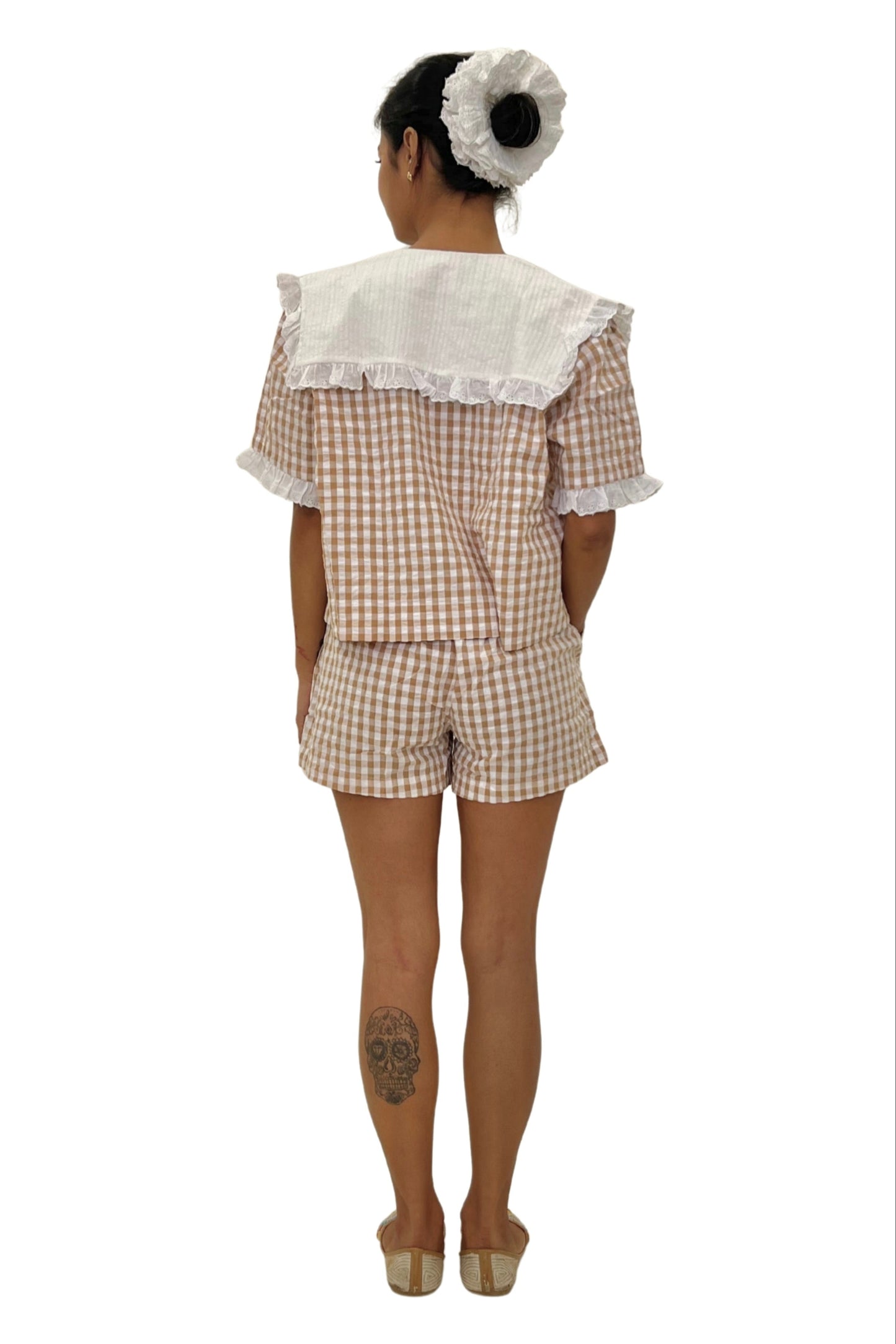 Person wearing a checkered outfit with lace details on a white background
