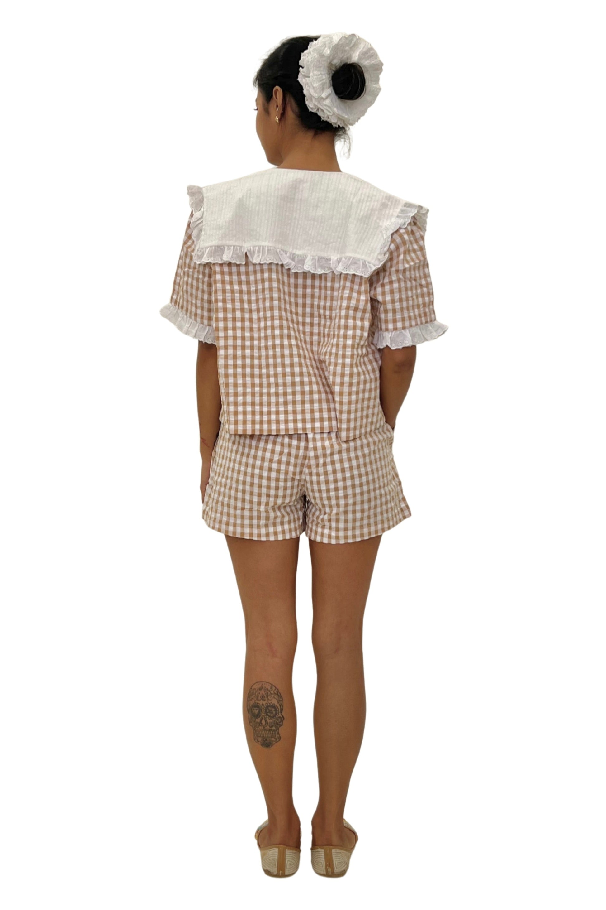 Person wearing a checkered outfit with lace details on a white background