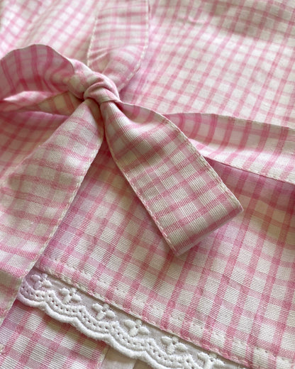Close-up of pink and white checkered waistcoat with a lace trim and back bow