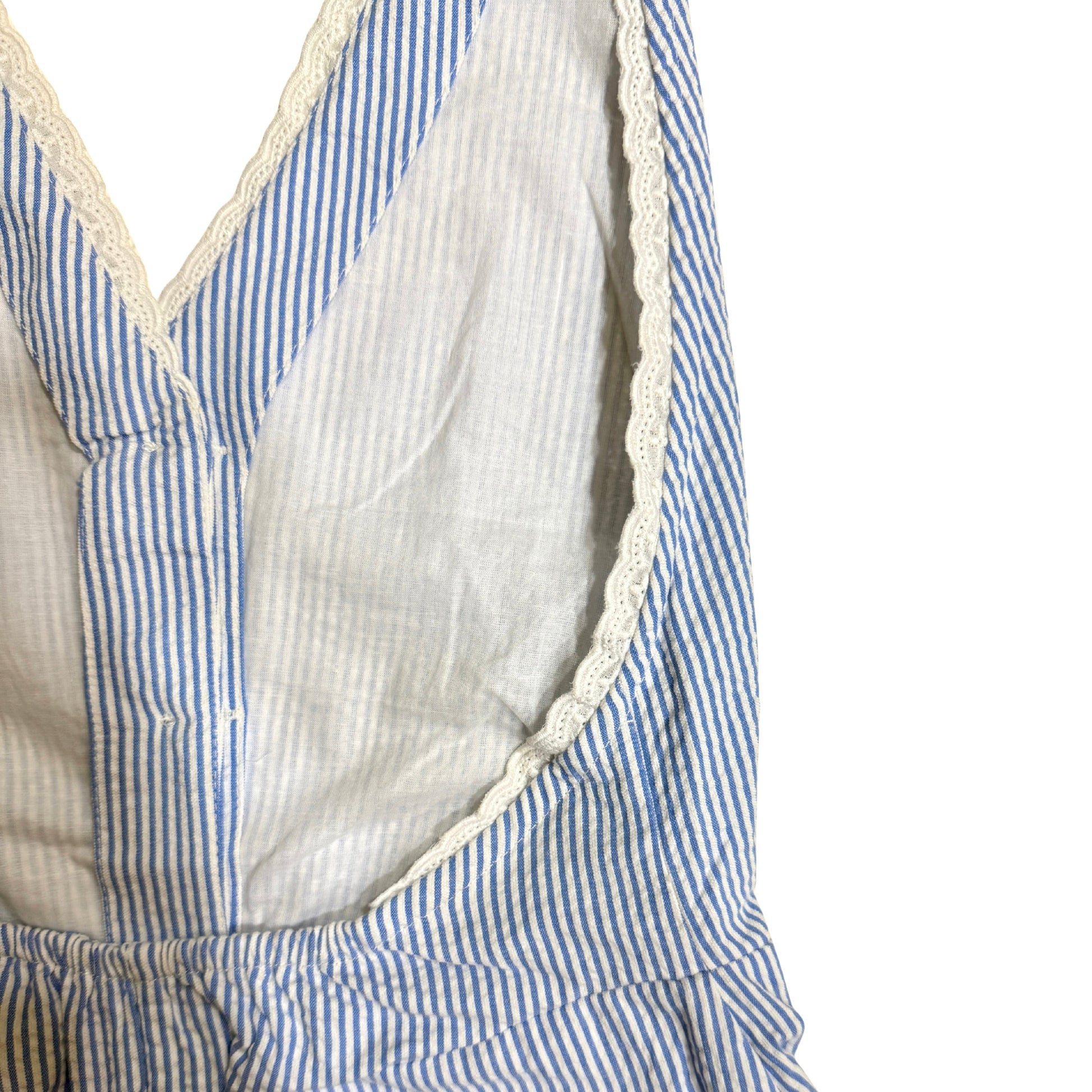 Close-up of a blue and white striped jumpsuit with white lace on a white background