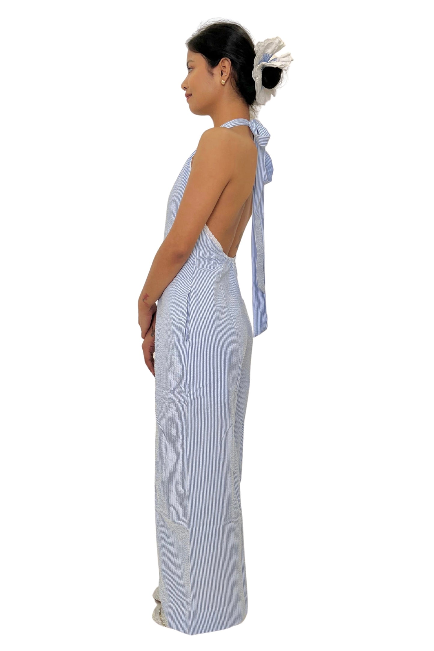 Woman wearing a white and blue striped jumpsuit with a bow detail on a white background