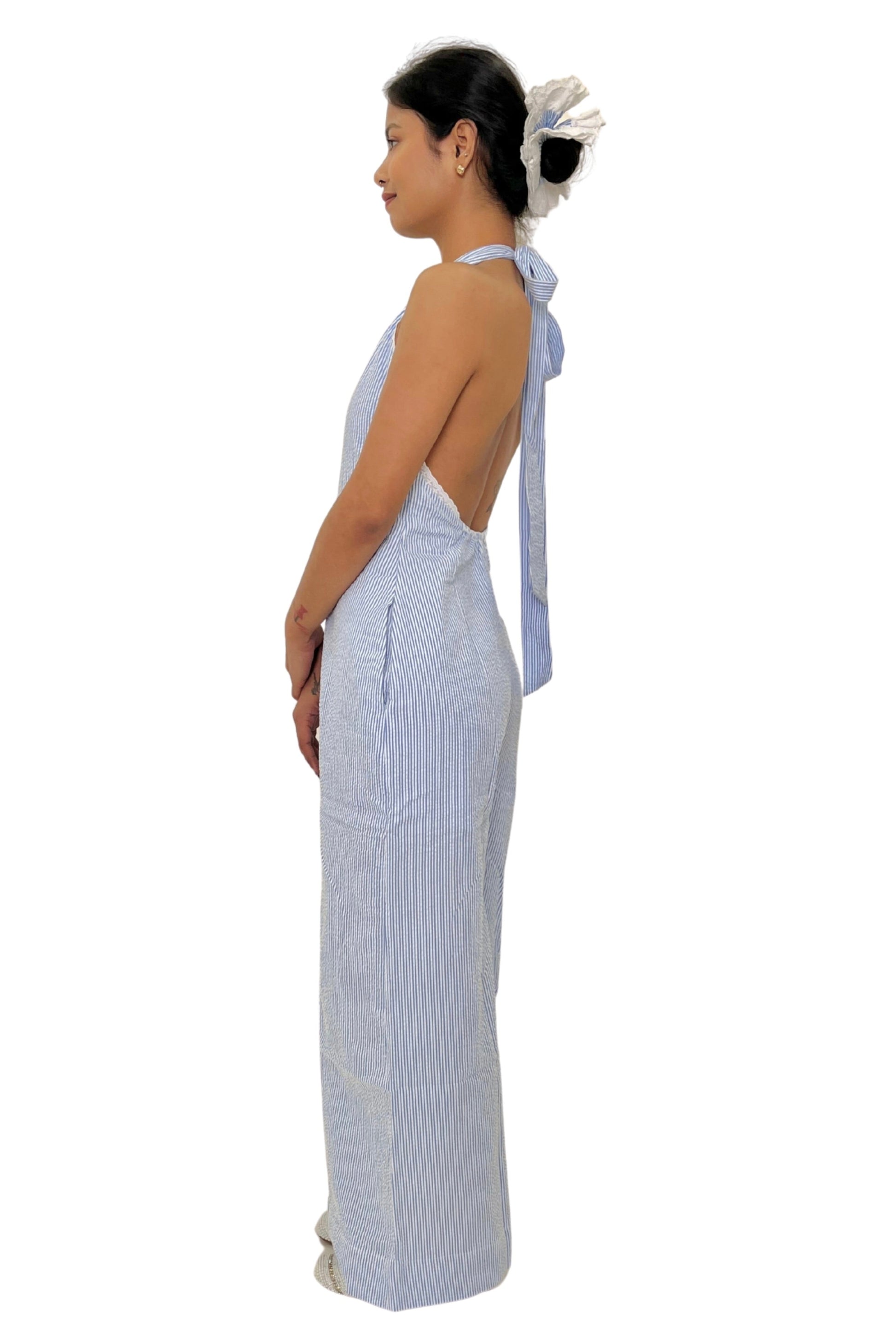 Woman wearing a white and blue striped jumpsuit with a bow detail on a white background