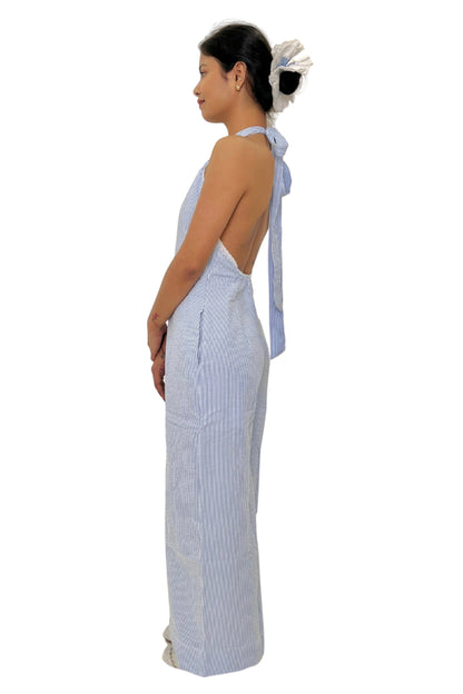 Woman wearing a white and blue striped jumpsuit with a bow detail on a white background