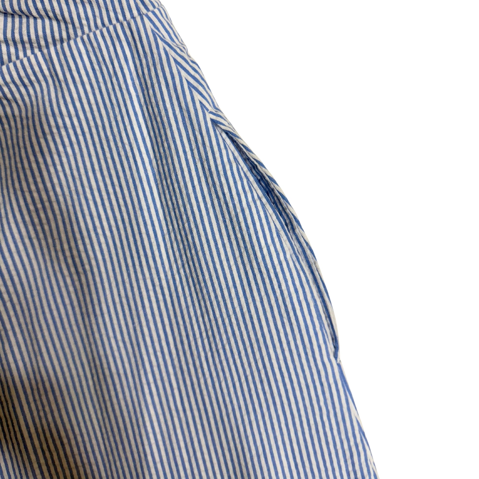 Close-up of a blue and white striped jumpsuit with lace trim on a white background