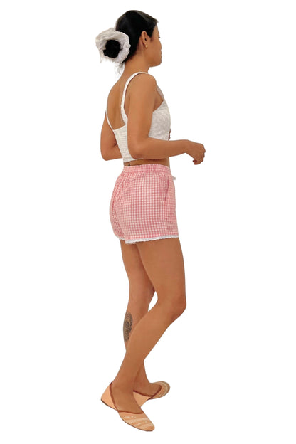 Model wearing a white lace top and pink checkered shorts on a white background
