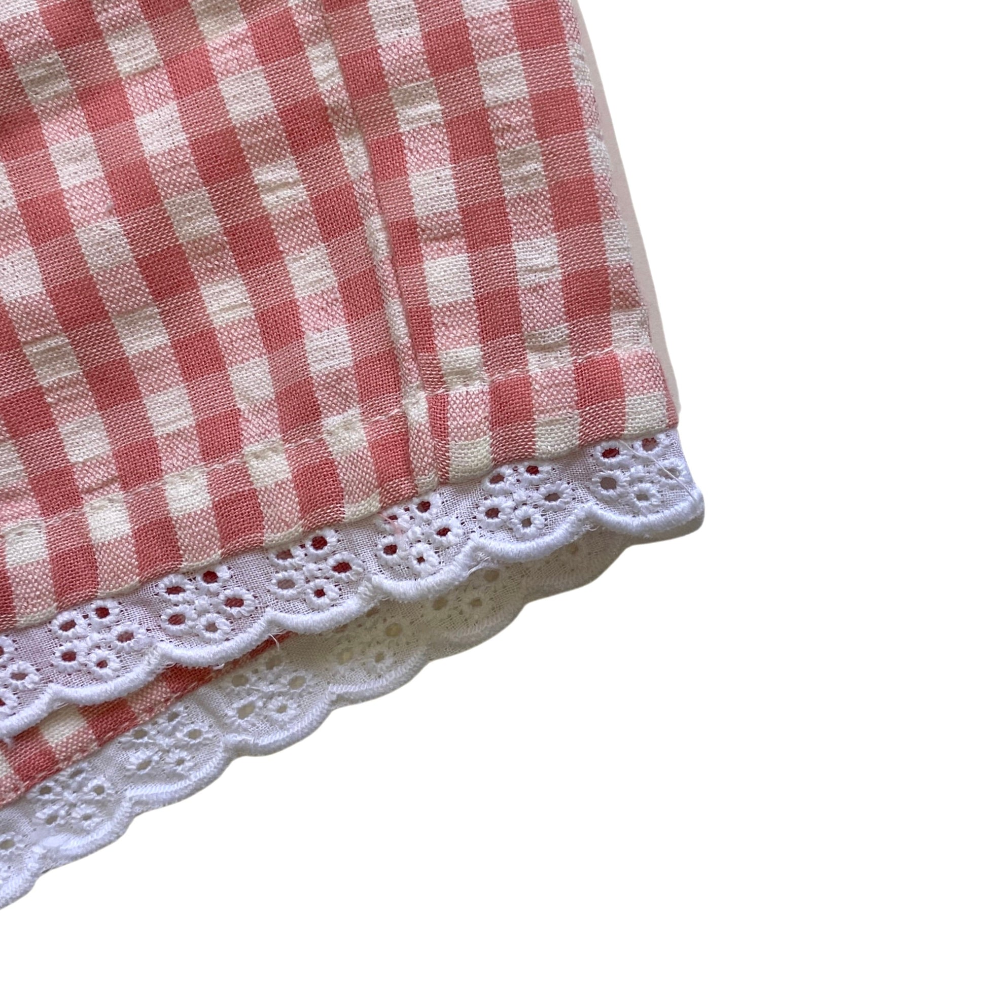 Pink and white checkered fabric with lace trim on a white background